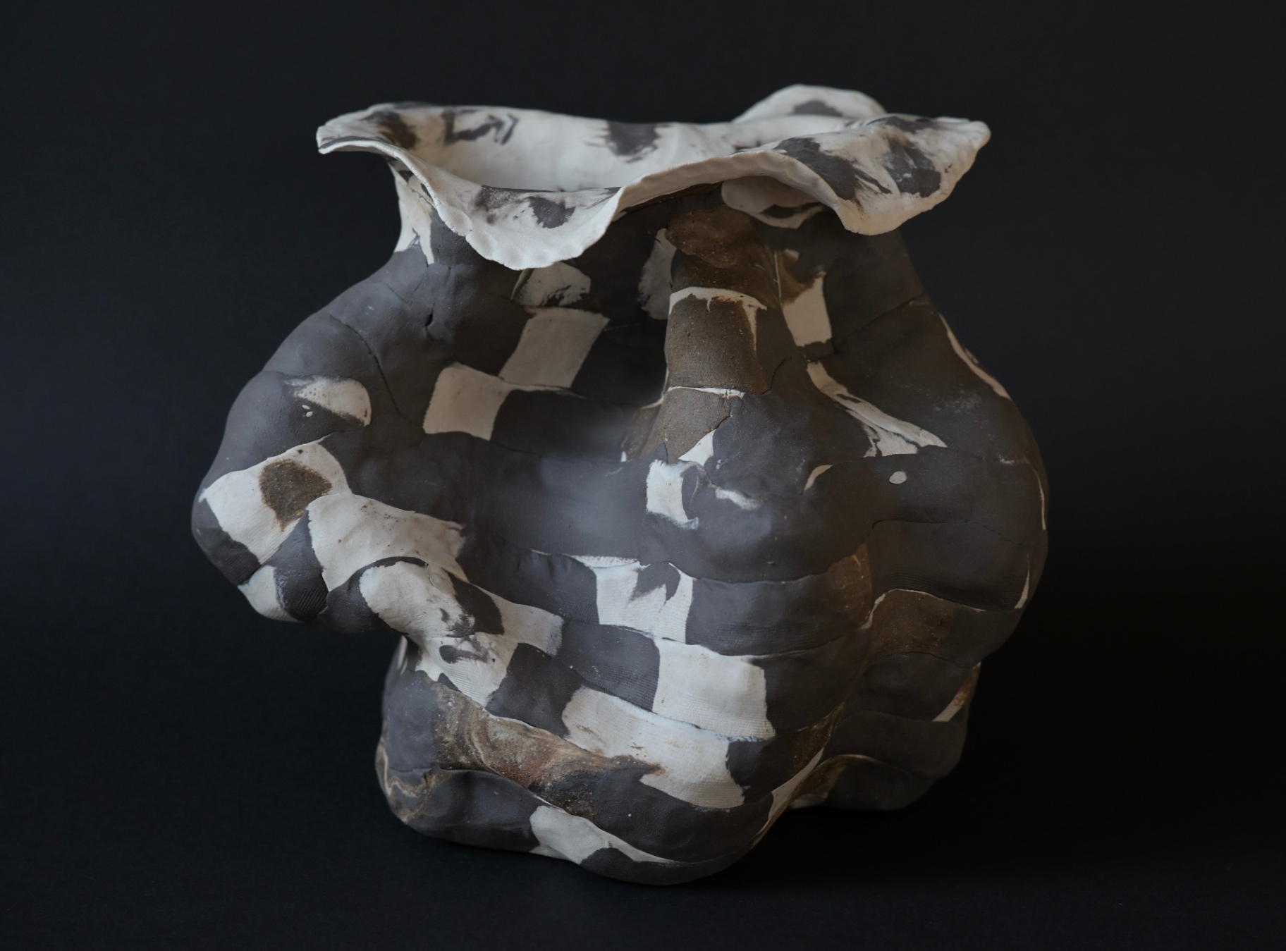 Unearthed, fragments of dark and pale clay gathered into an excavated form