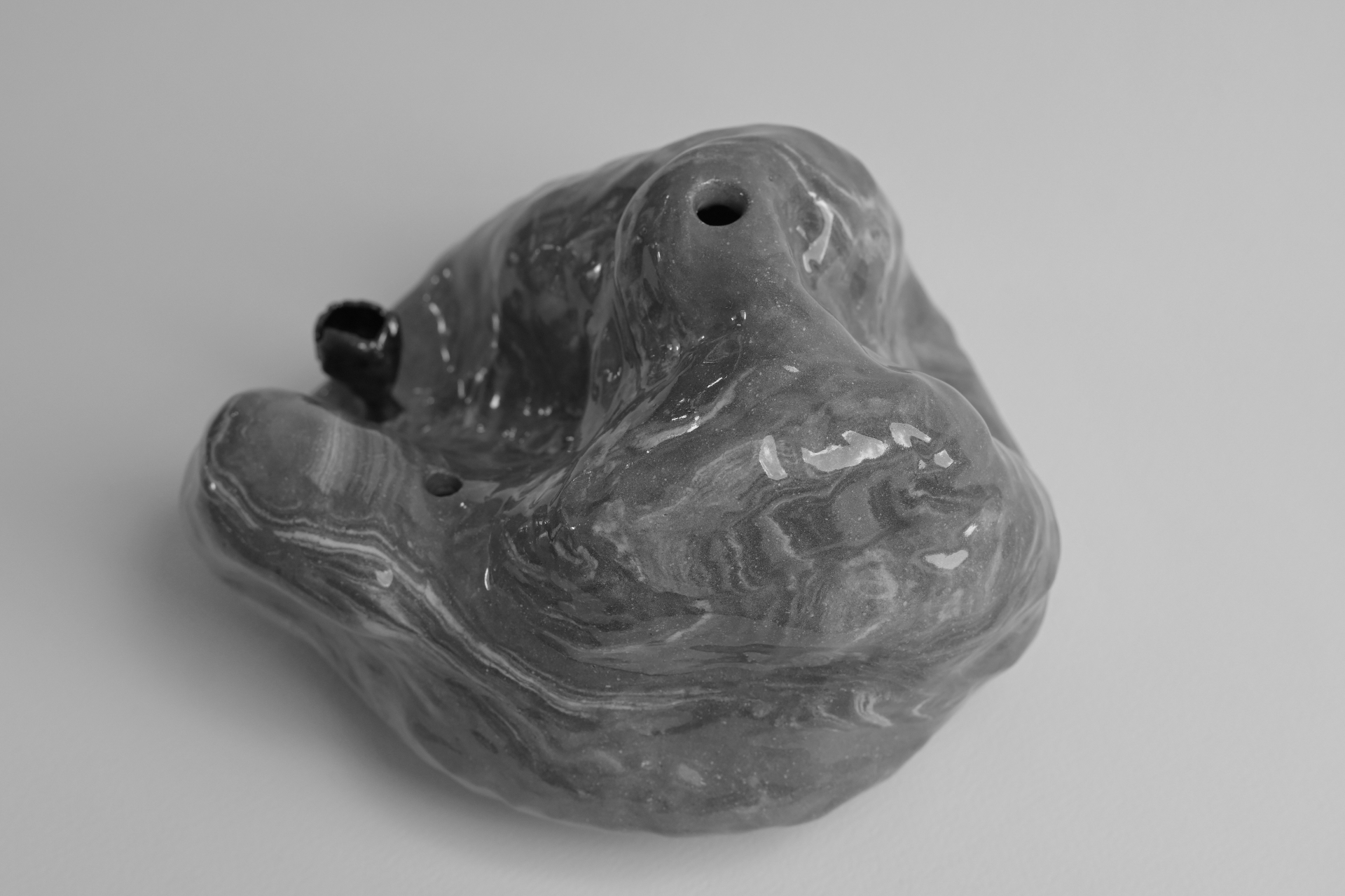 Afterimage, fluid marbled form with glossy surfaces and a small metallic bloom