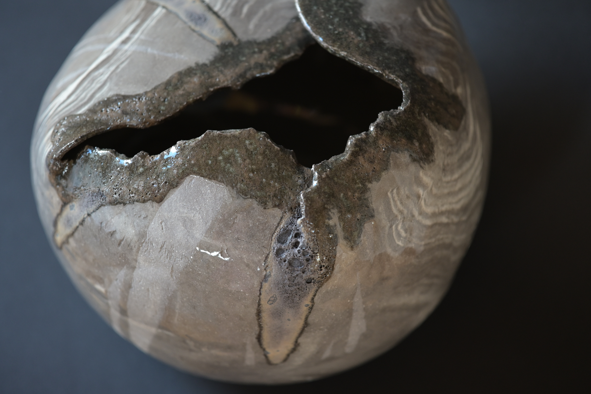Detail of a fired marbled stoneware form with layered clay and metallic glaze.